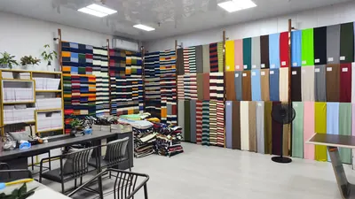 Phòng mẫu treo vải kẻ sọc và vải trơn nhiều màu tại một cửa hàng trong chợ vải, 5/2026.