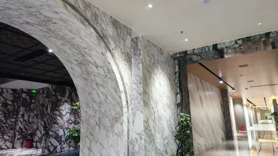 Tường và vòm ốp tấm vân đá khổ lớn tại một showroom vật liệu, 5/2026.
